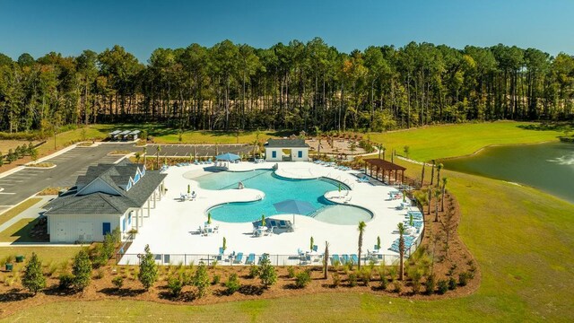 view of pool with a patio, a water view, and a lawn