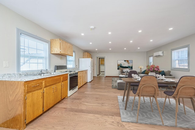 kitchen featuring a wall mounted air conditioner, light hardwood / wood-style flooring, sink, and white appliances