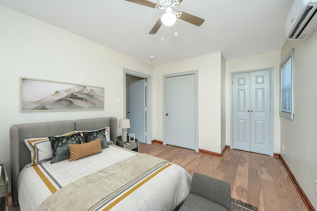 bedroom with a wall unit AC, wood-type flooring, and ceiling fan