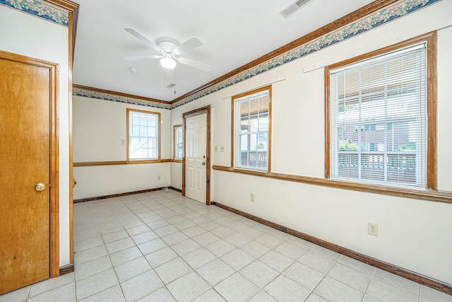 tiled empty room with ornamental molding and ceiling fan