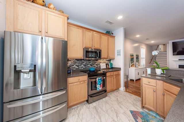 kitchen with decorative backsplash, light brown cabinetry, and appliances with stainless steel finishes