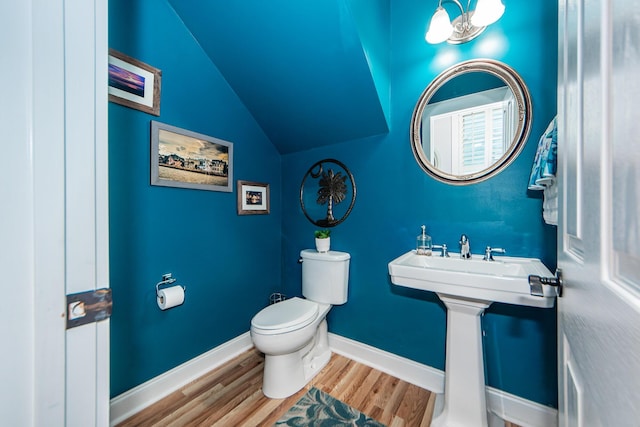 bathroom featuring wood-type flooring, toilet, and lofted ceiling