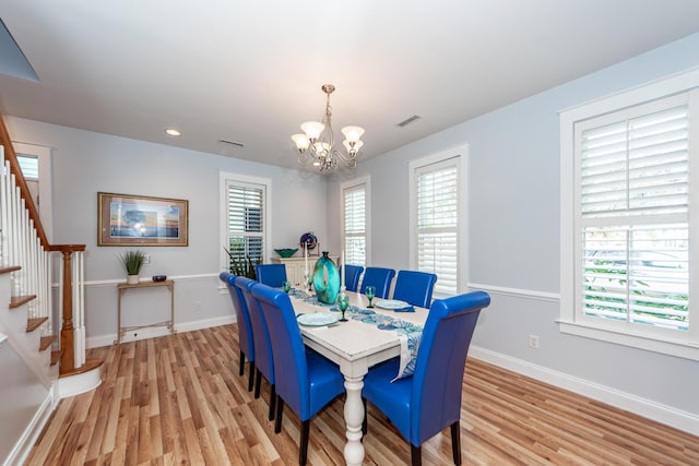 dining space with light wood-type flooring and an inviting chandelier