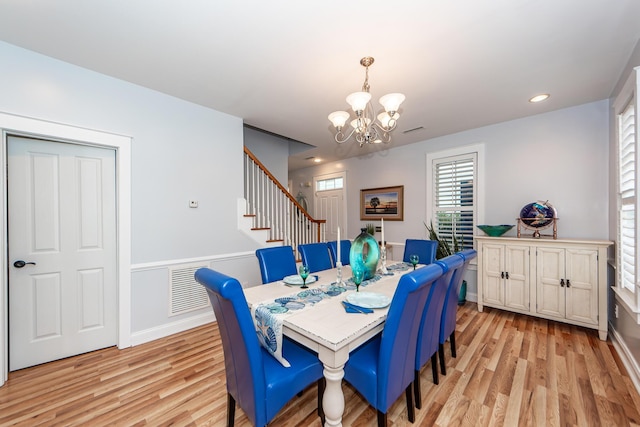 dining space featuring light hardwood / wood-style floors and an inviting chandelier