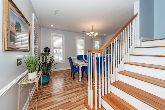 stairs featuring wood-type flooring and a notable chandelier