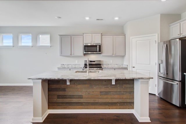 104 Wild Orchid Way, Huger, SC 29450 - kitchen featuring appliances with stainless steel finishes, light stone counters, an island with sink, dark wood-style flooring, and recessed lighting