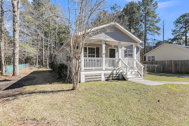 view of front of property featuring a front yard, covered porch, fence, and ceiling fan