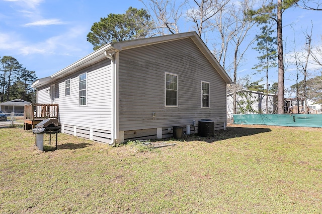 view of property exterior with a covered pool, a lawn, fence, and central AC unit