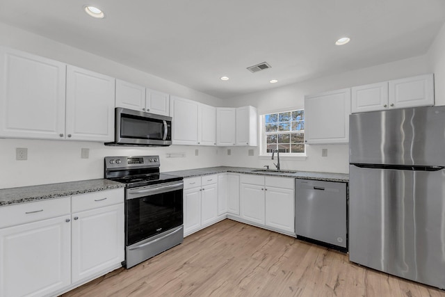 kitchen with a sink, visible vents, white cabinetry, appliances with stainless steel finishes, and light wood-type flooring