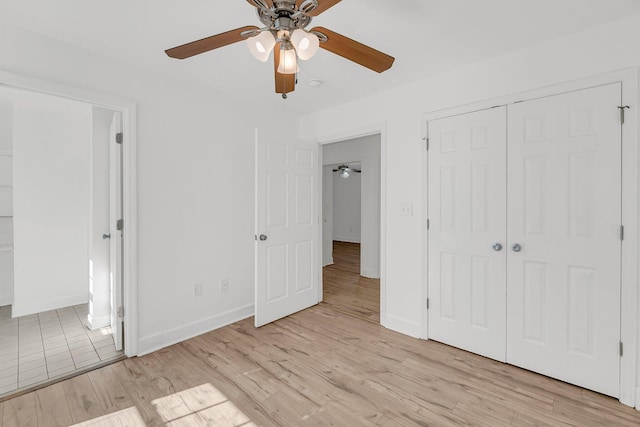 unfurnished bedroom with light wood-style floors, a closet, baseboards, and a ceiling fan