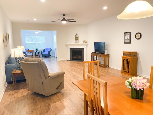 living room with light wood finished floors, baseboards, a ceiling fan, a fireplace with flush hearth, and recessed lighting