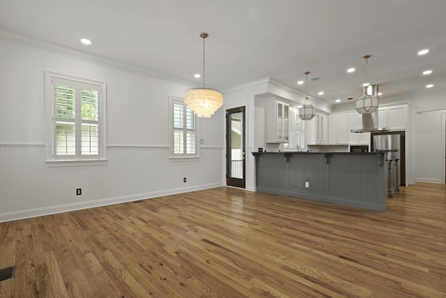 2258 Arthur Gaillard Ln, Charleston, SC 29414 - kitchen with a chandelier, wood finished floors, a breakfast bar, white cabinets, and glass insert cabinets