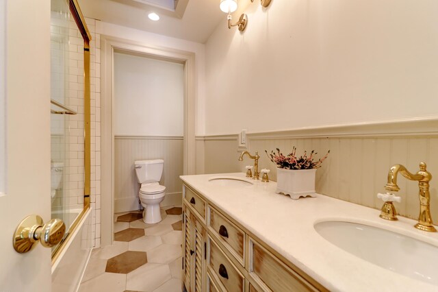 full bathroom featuring toilet, bath / shower combo with glass door, and vanity