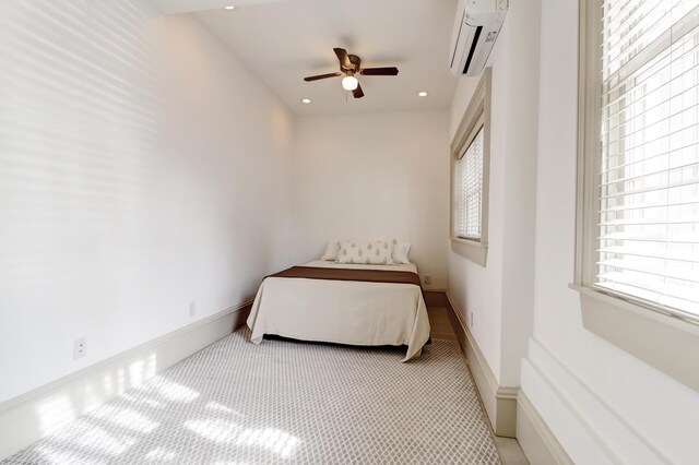 bedroom featuring light colored carpet, ceiling fan, and an AC wall unit