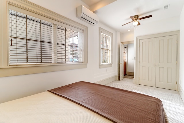 unfurnished bedroom featuring a wall mounted AC, ceiling fan, light carpet, and a closet