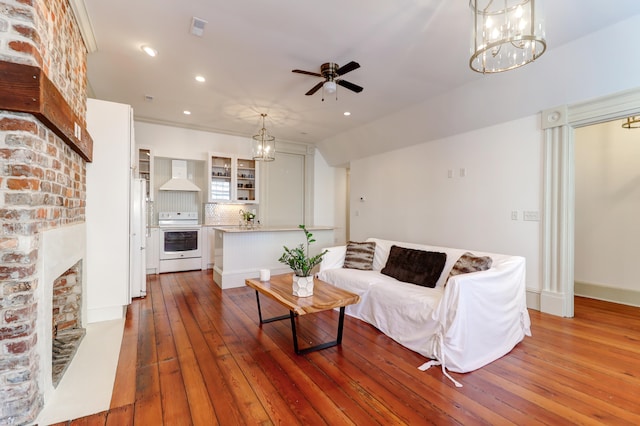 living room featuring hardwood / wood-style floors, ceiling fan with notable chandelier, and a fireplace