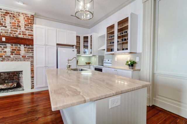 kitchen with white appliances, hanging light fixtures, and an island with sink