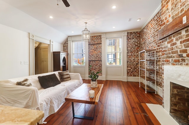 living room featuring brick wall, dark hardwood / wood-style floors, ceiling fan with notable chandelier, a brick fireplace, and lofted ceiling