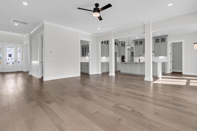 unfurnished living room with crown molding, sink, hardwood / wood-style flooring, and ceiling fan