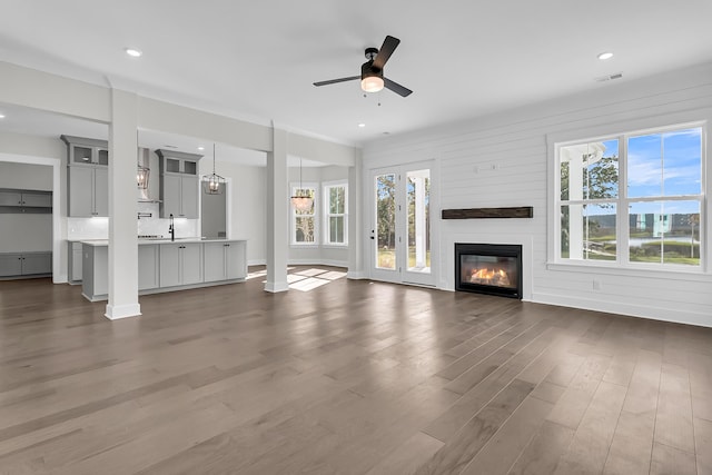 unfurnished living room with ceiling fan, a large fireplace, a wealth of natural light, and dark hardwood / wood-style flooring