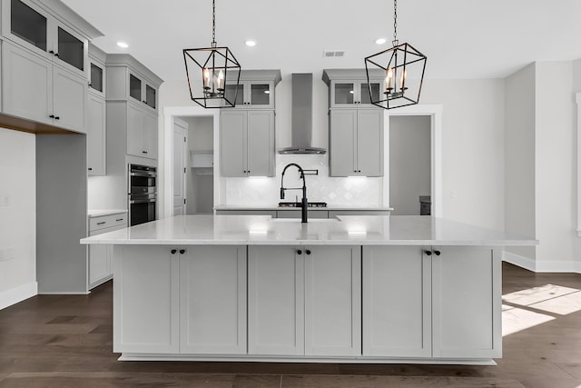 kitchen featuring an inviting chandelier, a spacious island, hanging light fixtures, and wall chimney exhaust hood