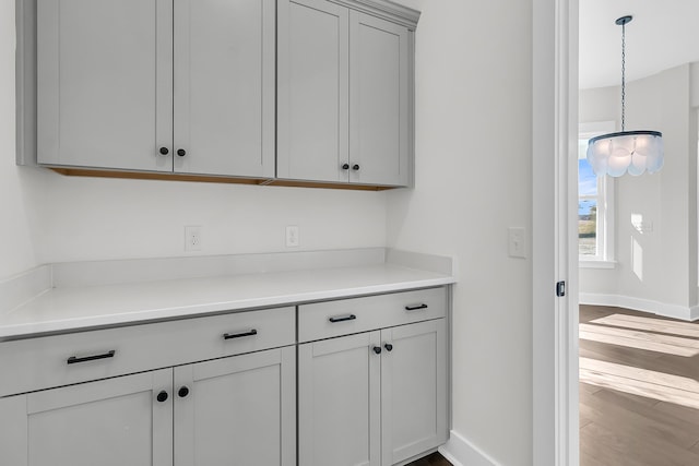 interior space with gray cabinetry, pendant lighting, and wood-type flooring