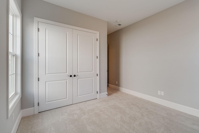 unfurnished bedroom featuring light colored carpet and a closet