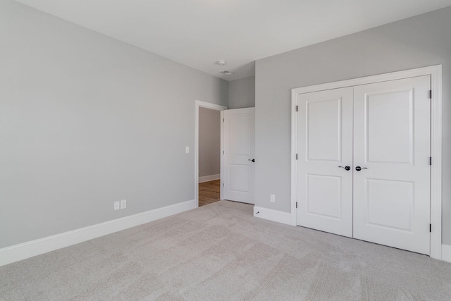 unfurnished bedroom featuring light carpet and a closet