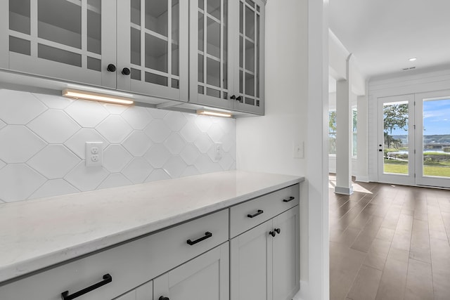 kitchen with white cabinetry, decorative backsplash, light stone countertops, and hardwood / wood-style flooring