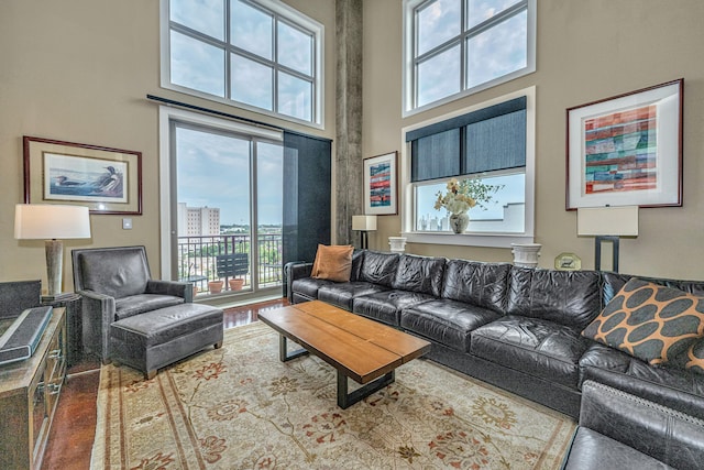 living room featuring a healthy amount of sunlight, a towering ceiling, and hardwood / wood-style flooring