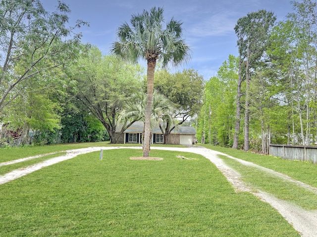 exterior space featuring a front lawn, fence, a garage, and driveway