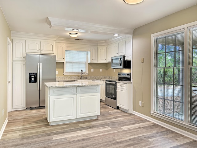 kitchen with stainless steel appliances, light wood-style flooring, white cabinetry, and baseboards