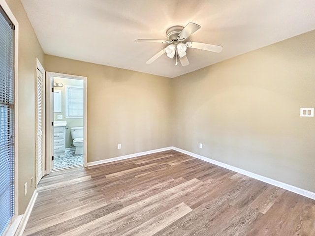 unfurnished bedroom featuring baseboards, connected bathroom, and wood finished floors