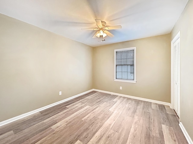 spare room featuring ceiling fan, baseboards, and wood finished floors