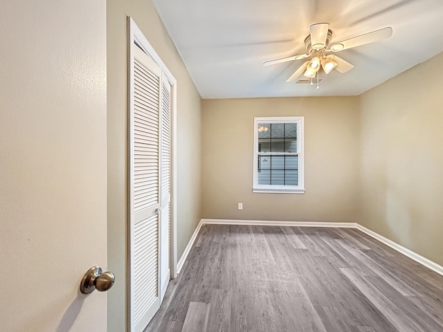 unfurnished bedroom featuring a closet, baseboards, ceiling fan, and wood finished floors