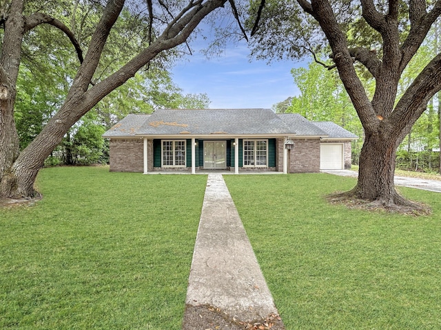 ranch-style house with a front yard, a shingled roof, a garage, concrete driveway, and brick siding