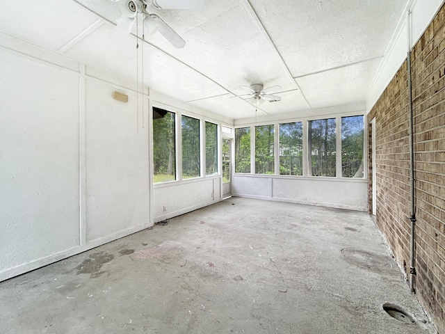 unfurnished sunroom featuring a ceiling fan and a healthy amount of sunlight