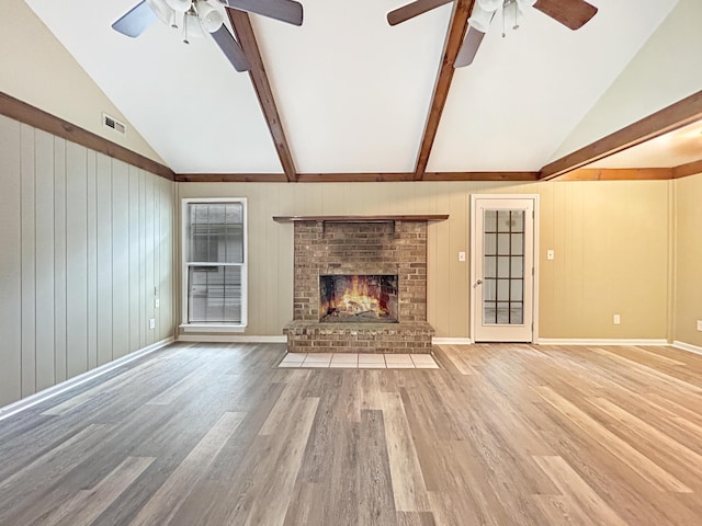 unfurnished living room with ceiling fan, vaulted ceiling with beams, and wood finished floors
