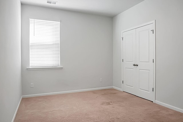 unfurnished bedroom with carpet flooring, baseboards, and visible vents