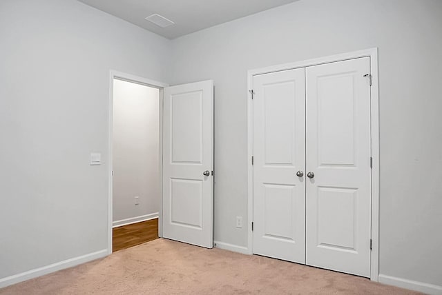 unfurnished bedroom with light carpet, visible vents, a closet, and baseboards