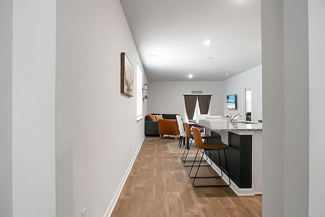 hallway with recessed lighting, light wood-style flooring, and baseboards