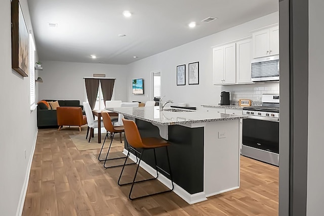 kitchen featuring visible vents, a sink, light wood-style floors, appliances with stainless steel finishes, and open floor plan