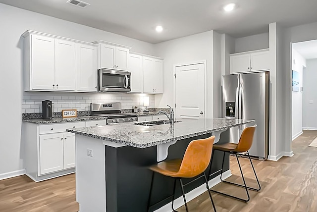 kitchen featuring a sink, tasteful backsplash, appliances with stainless steel finishes, and light wood finished floors