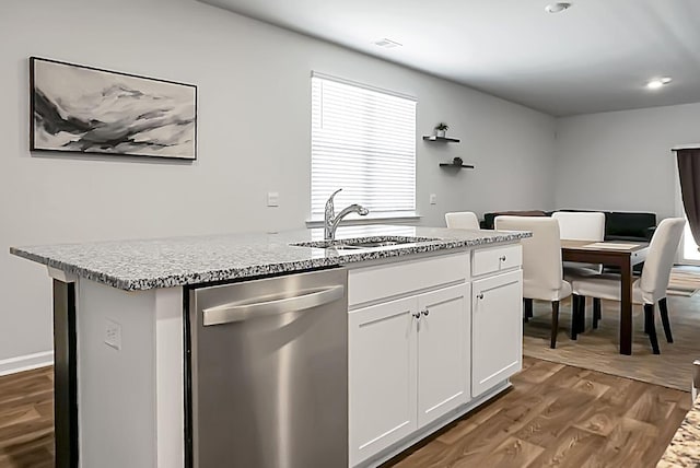 kitchen featuring a kitchen island with sink, a sink, wood finished floors, white cabinetry, and dishwasher