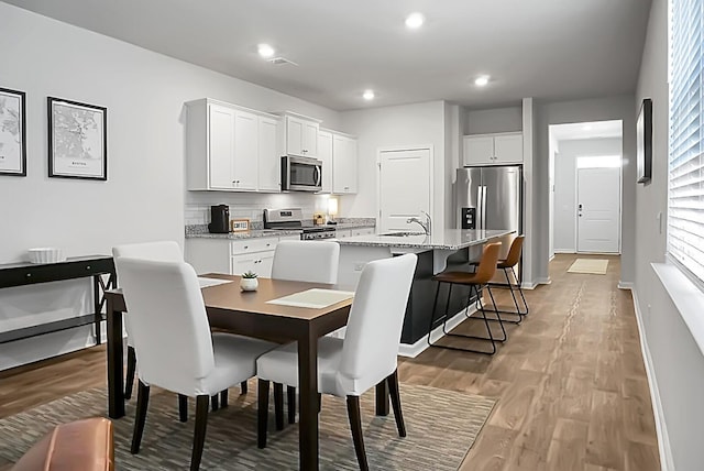 dining room with recessed lighting, baseboards, and light wood finished floors