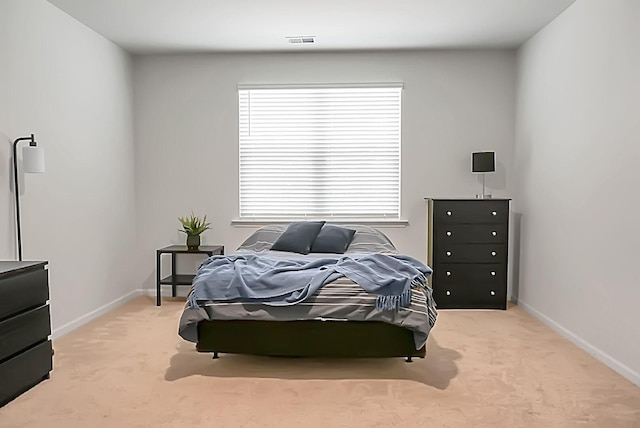 bedroom featuring baseboards, visible vents, and light carpet