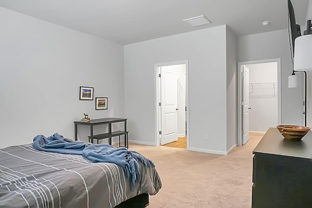 bedroom with a spacious closet, baseboards, and light carpet