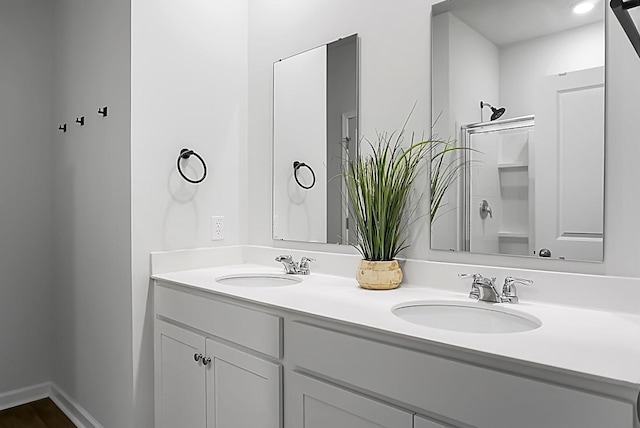 full bath with double vanity, baseboards, and a sink