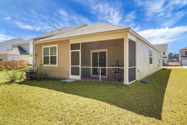 back of property featuring central AC unit, fence, a yard, and a sunroom