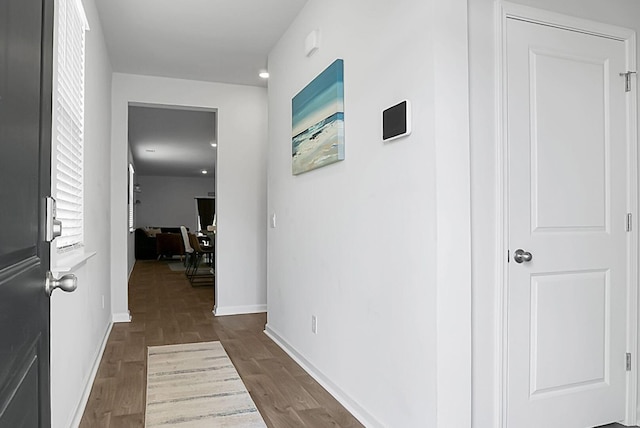 hall featuring baseboards and dark wood-style flooring